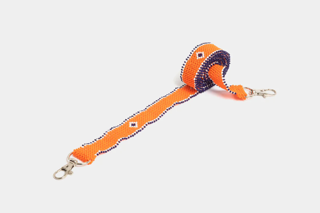 Bandoulière en perles colorées "Alvaro" dans la couleur "Simple Orange." Disponible en plusieurs autres coloris, avec certains modèles uniques. Longueur de 115 à 120 cm. Fabriquée à la main au Kenya: