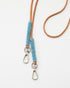 Bandoulière fine en cuir brun ornée de perles bleu clair, modèle "Charo" conçu pour être amovible et adaptable à un sac ou une coque de téléphone. Accessoire élégant, réalisé à la main par un artisan au Kenya, disponible en deux longueurs (90 cm et 110 cm).