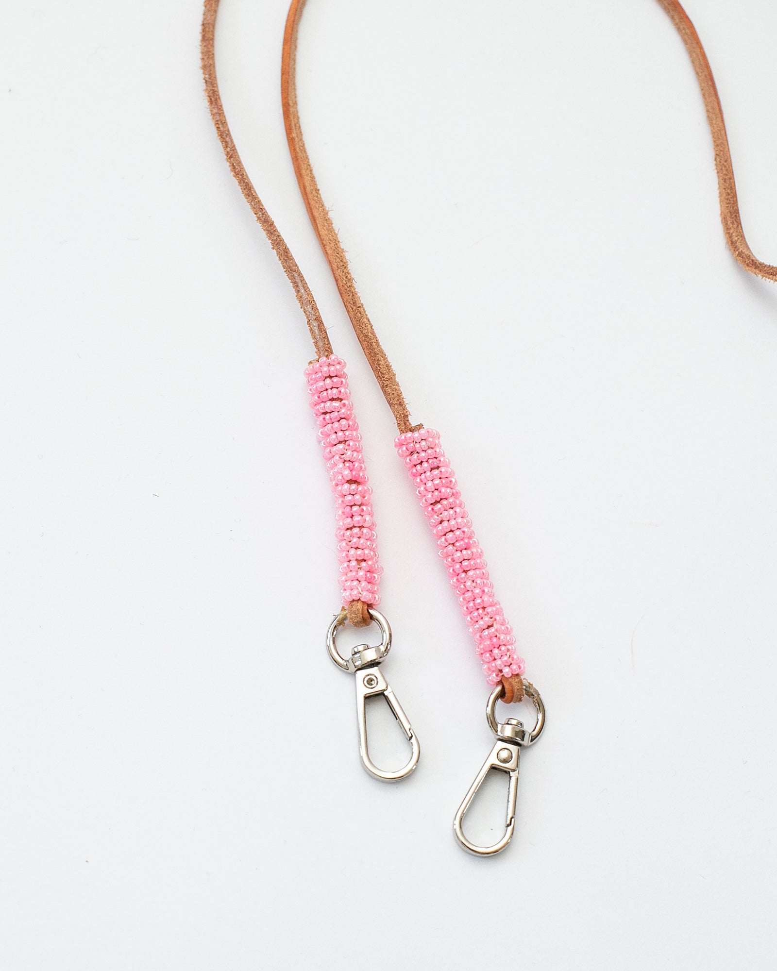 Bandoulière fine en cuir brun ornée de perles roses, modèle "Charu" conçu pour être amovible et adaptable à un sac ou une coque de téléphone. Accessoire élégant, réalisé à la main par un artisan au Kenya, disponible en deux longueurs (90 cm et 110 cm).